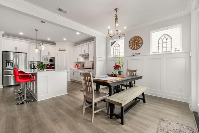 4372 Spregan Way, Smyrna, TN 37167 - dining area featuring an inviting chandelier, a decorative wall, light wood-style flooring, and wainscoting