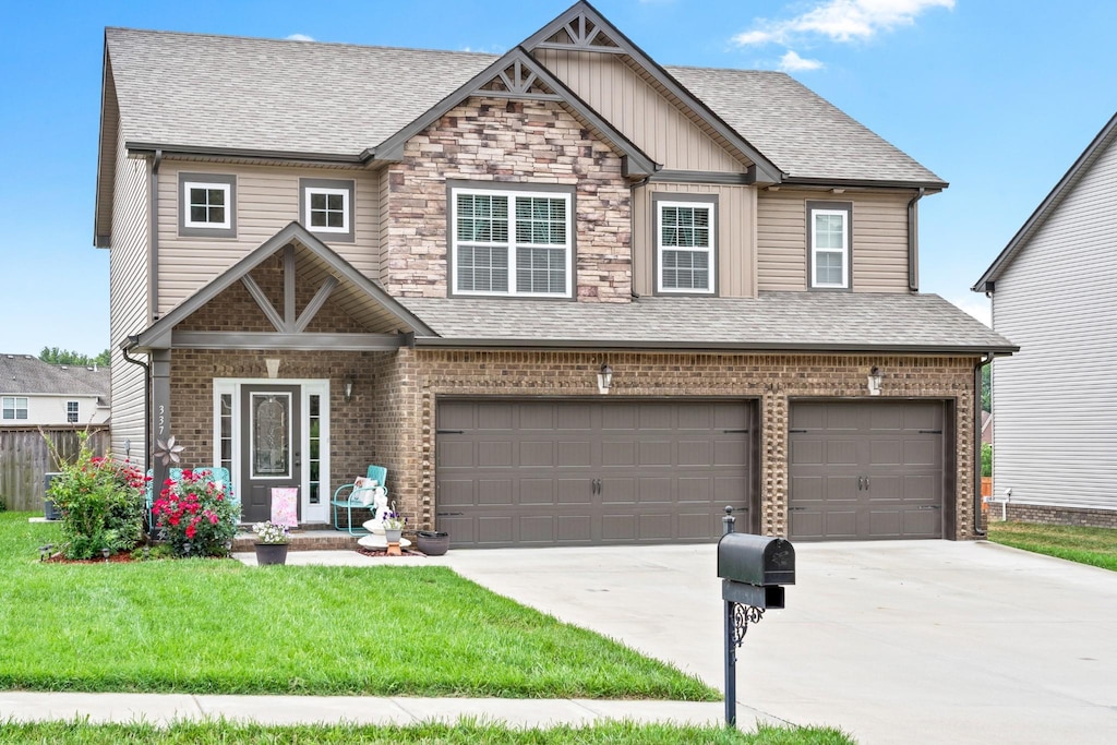 craftsman house featuring roof with shingles, a front yard, driveway, and an attached garage
