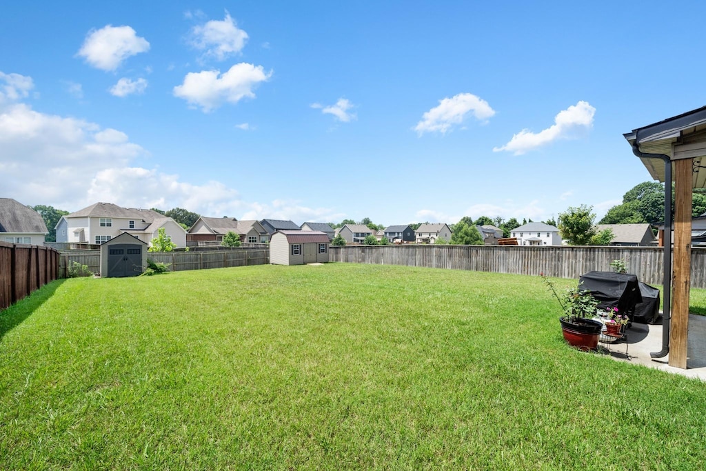 view of yard featuring a storage unit, an outbuilding, a residential view, and a fenced backyard