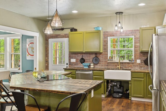 kitchen featuring pendant lighting, green cabinetry, a sink, appliances with stainless steel finishes, and dark wood-type flooring