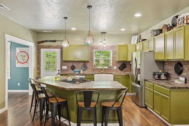 kitchen with black electric stovetop, a breakfast bar area, a kitchen island, green cabinets, and a sink