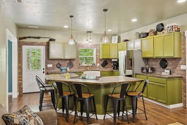 kitchen with a breakfast bar area, green cabinetry, a healthy amount of sunlight, and freestanding refrigerator
