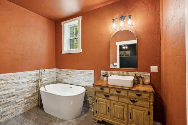 full bathroom with vanity, a soaking tub, a textured wall, and tile walls