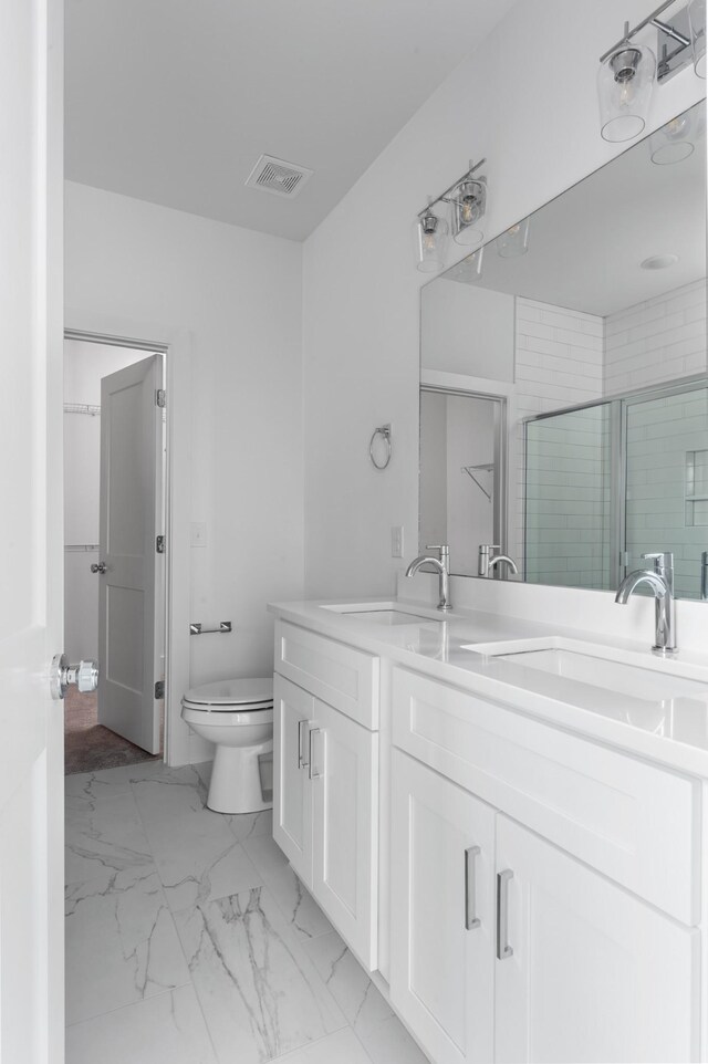 bathroom with a shower stall, marble finish floor, toilet, and a sink
