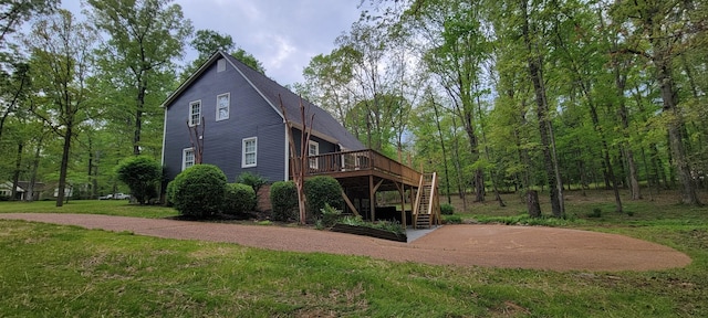 back of property with a deck, a lawn, and stairs