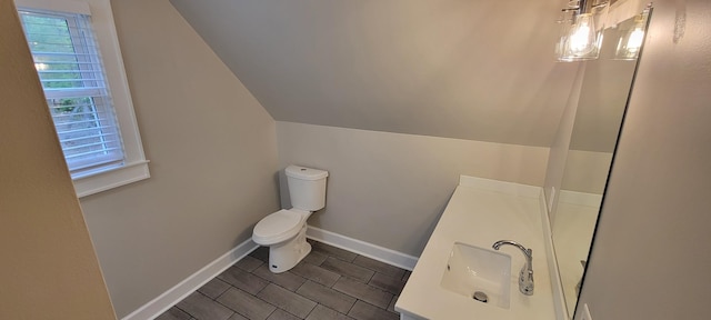 bathroom with vanity, toilet, vaulted ceiling, and baseboards