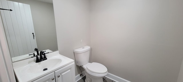 bathroom featuring toilet, vanity, and baseboards