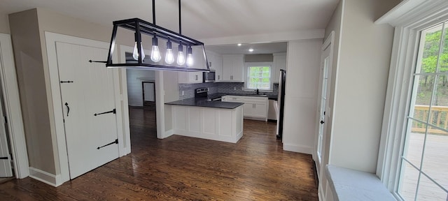 kitchen featuring stainless steel appliances, dark countertops, backsplash, dark wood-style flooring, and white cabinetry