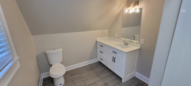 bathroom featuring toilet, vaulted ceiling, vanity, and baseboards