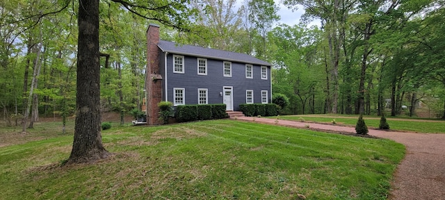 colonial house with a front yard and a chimney