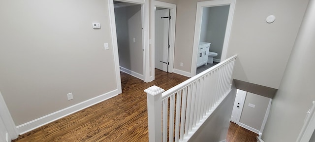 hall with an upstairs landing, dark wood-type flooring, and baseboards