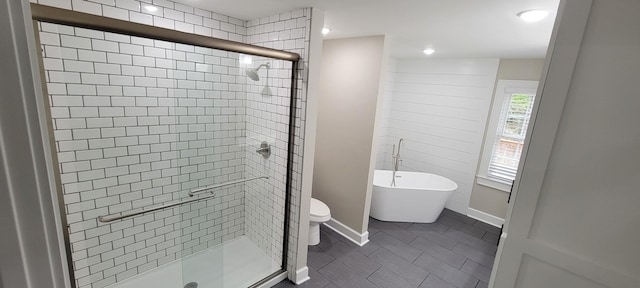 bathroom featuring a stall shower, baseboards, toilet, tile patterned floors, and a freestanding bath