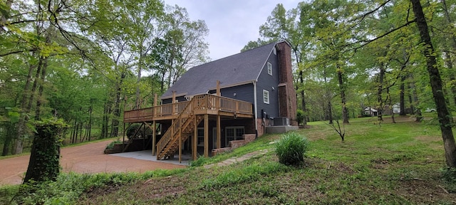 rear view of house with stairs, a patio, a wooden deck, a shingled roof, and a lawn