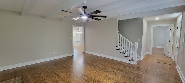spare room featuring wood finished floors, baseboards, stairway, a ceiling fan, and beam ceiling