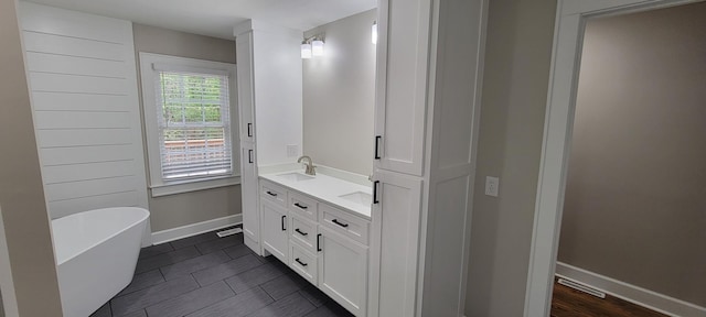 full bath featuring a sink, double vanity, visible vents, baseboards, and a freestanding bath