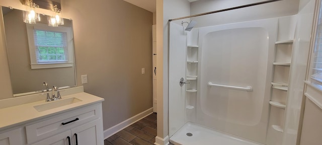 full bath featuring a stall shower, baseboards, wood finished floors, and vanity