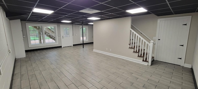 below grade area with a paneled ceiling, visible vents, stairway, and baseboards
