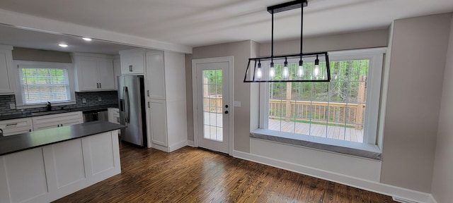 kitchen featuring a sink, stainless steel appliances, backsplash, white cabinetry, and dark countertops