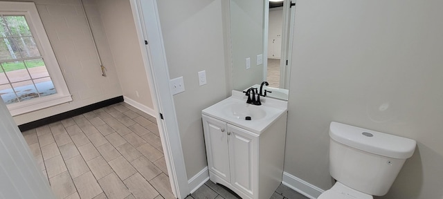 half bath featuring toilet, vanity, and baseboards