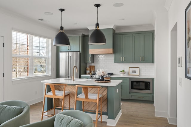 kitchen with a sink, green cabinets, light countertops, high end fridge, and built in microwave