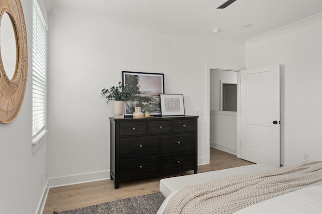 bedroom featuring baseboards, light wood-type flooring, and ornamental molding
