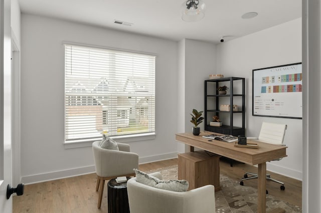 office area featuring baseboards, visible vents, and wood finished floors