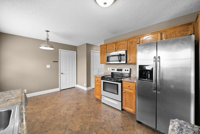 2938 Heatherfield Dr, Woodlawn, TN 37191 - kitchen featuring stainless steel appliances, baseboards, brown cabinetry, hanging light fixtures, and a textured ceiling