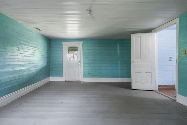 empty room with baseboards, wooden ceiling, and wood finished floors