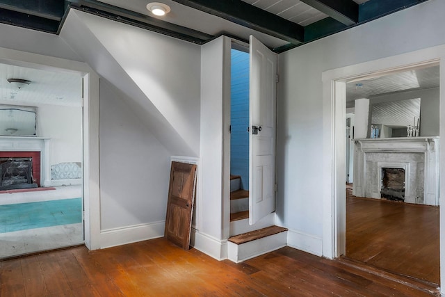 stairway with a fireplace, hardwood / wood-style flooring, beamed ceiling, and baseboards