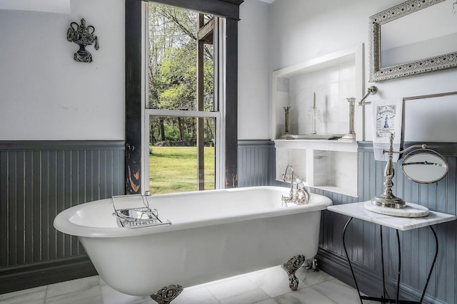 full bath with wainscoting, a freestanding bath, and marble finish floor