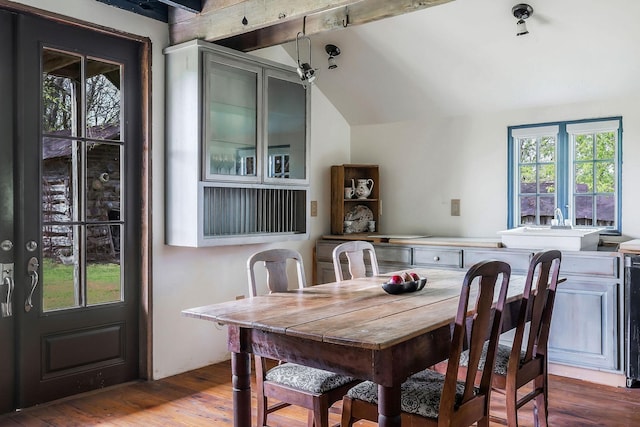dining room with vaulted ceiling with beams and wood finished floors