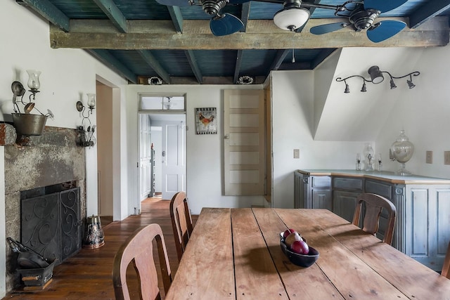 dining space featuring a fireplace, wood finished floors, and beamed ceiling