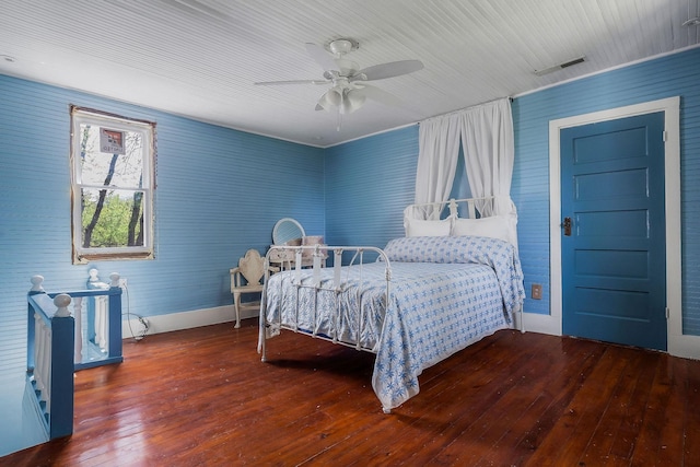 bedroom featuring a ceiling fan, visible vents, hardwood / wood-style flooring, and baseboards