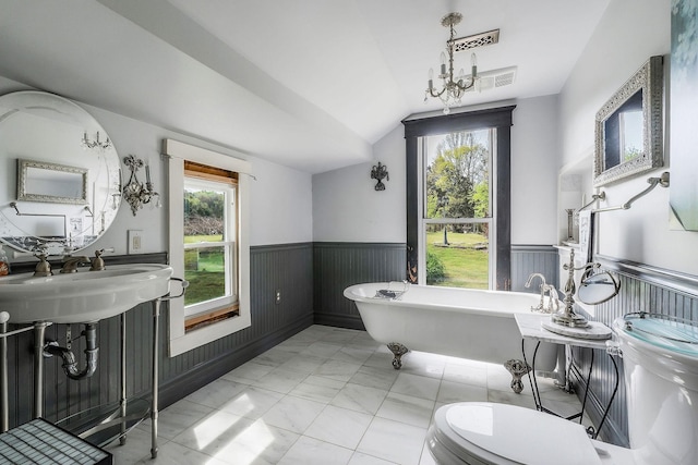 bathroom featuring wainscoting, a soaking tub, lofted ceiling, and plenty of natural light