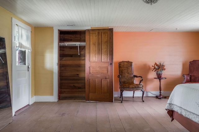 bedroom with wood walls, hardwood / wood-style floors, wooden ceiling, a closet, and baseboards