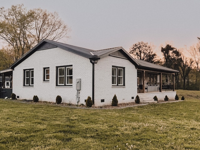 233 Garner Ln, Lawrenceburg, TN 38464 - property exterior at dusk featuring metal roof, covered porch, crawl space, a yard, and brick siding