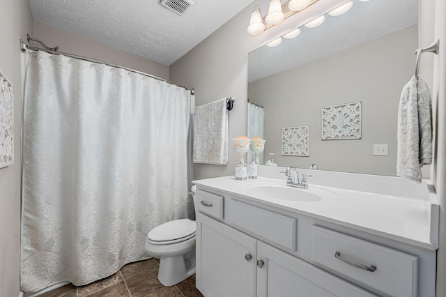 bathroom with a textured ceiling, visible vents, toilet, tile patterned floors, and vanity
