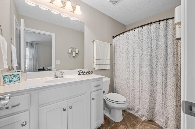 bathroom with a textured ceiling, vanity, toilet, and visible vents