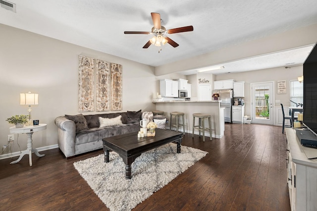 living area featuring visible vents, ceiling fan, dark wood-style flooring, and baseboards