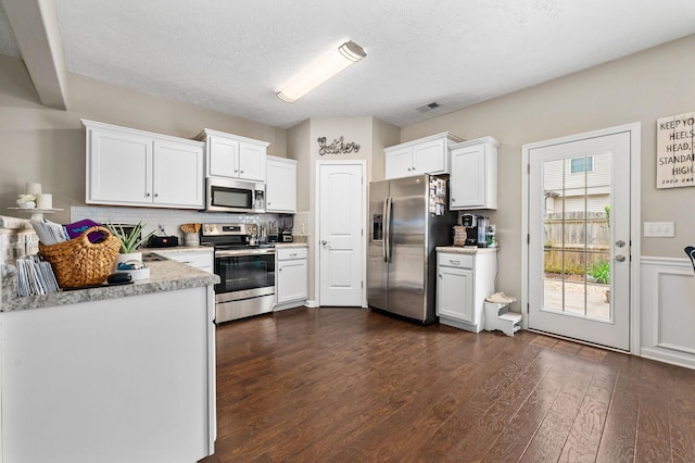 kitchen with white cabinetry, appliances with stainless steel finishes, visible vents, light countertops, and dark wood-style flooring