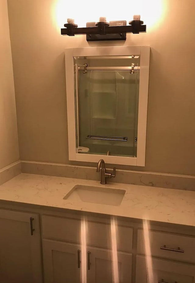 bathroom featuring toilet, an enclosed shower, and vanity