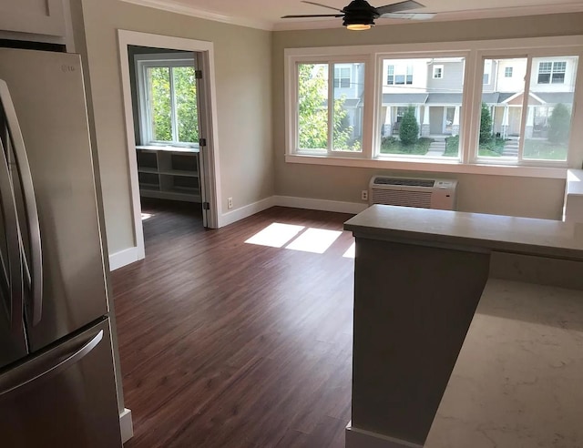 interior space featuring dark wood-style floors, a wall mounted AC, freestanding refrigerator, and baseboards
