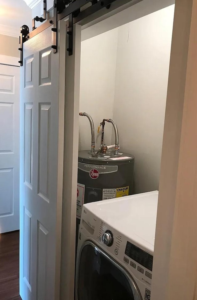 clothes washing area with a barn door, dark wood-style flooring, water heater, washer / dryer, and laundry area