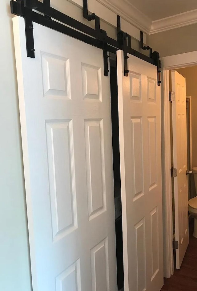 room details with a barn door, ornamental molding, and wood finished floors
