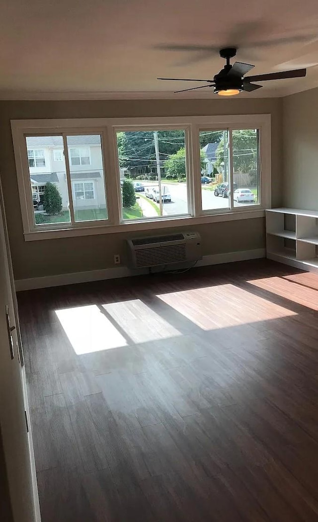 unfurnished room with baseboards, ceiling fan, dark wood-type flooring, and an AC wall unit