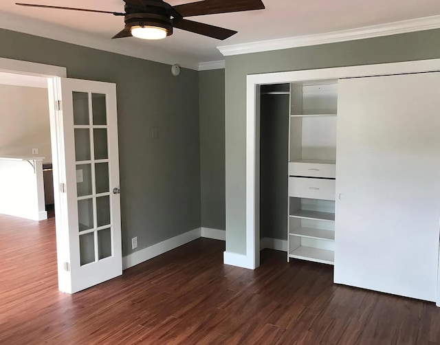 unfurnished bedroom featuring crown molding, dark wood-style floors, a closet, and baseboards