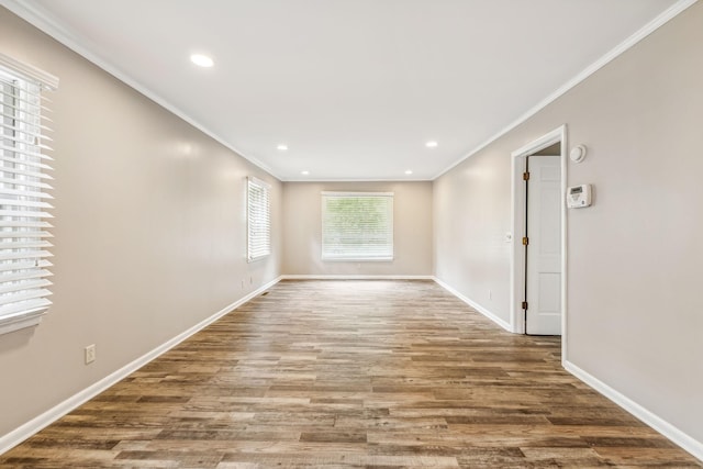spare room with crown molding, recessed lighting, wood finished floors, and baseboards