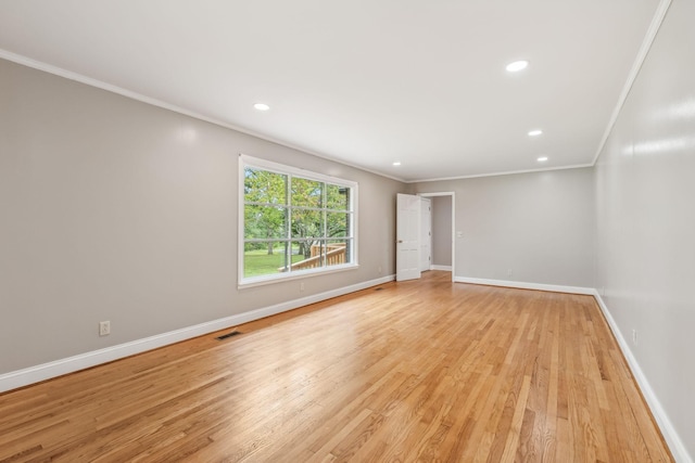 empty room with baseboards, visible vents, light wood finished floors, and crown molding