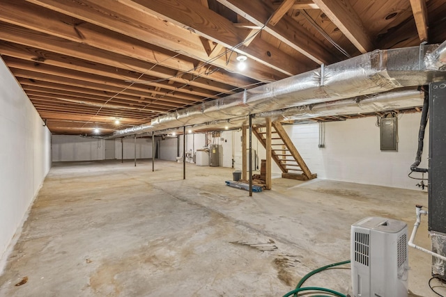 unfinished below grade area featuring water heater, stairs, and electric panel