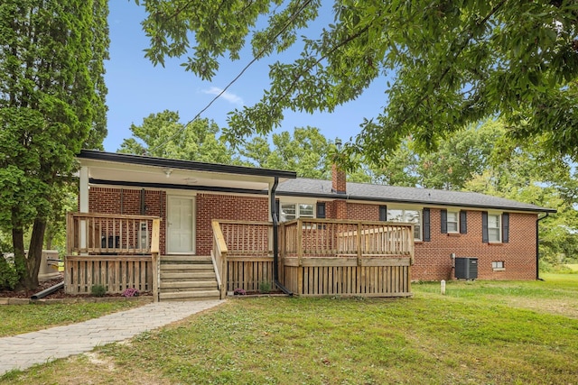 rear view of house featuring central AC, brick siding, a chimney, and a yard